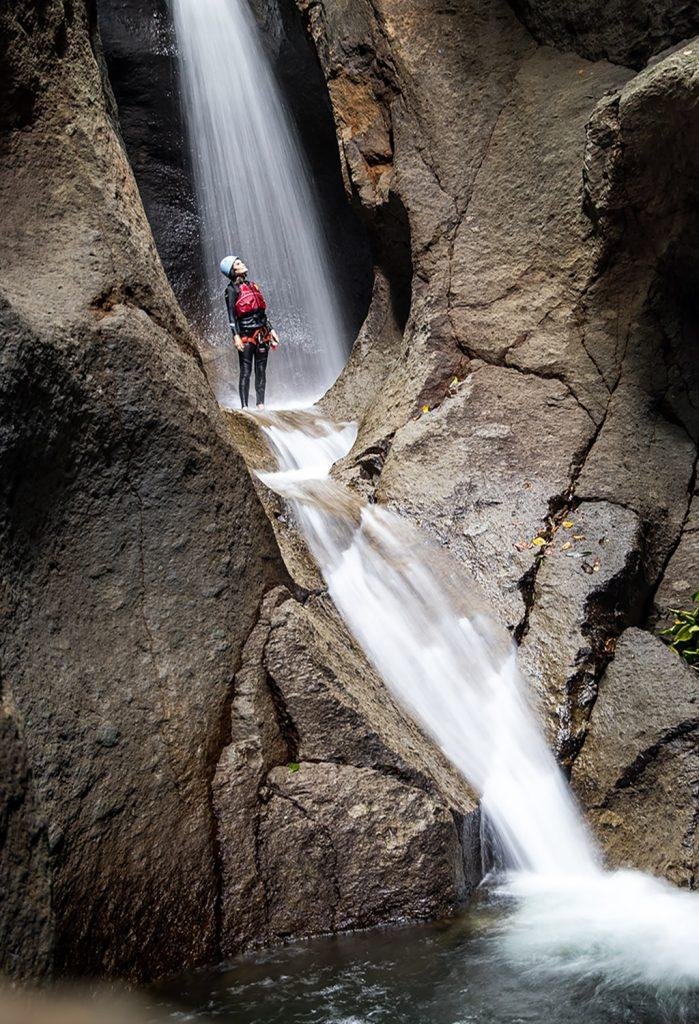 Person in hiking gear standing next to a waterfall